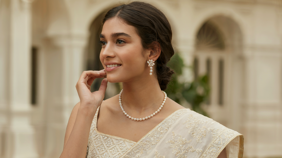 Model wearing a single-strand freshwater pearl necklace and drop earrings