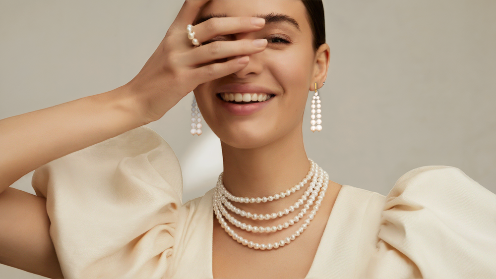 Smiling woman wearing a layered pearl necklace and drop earrings